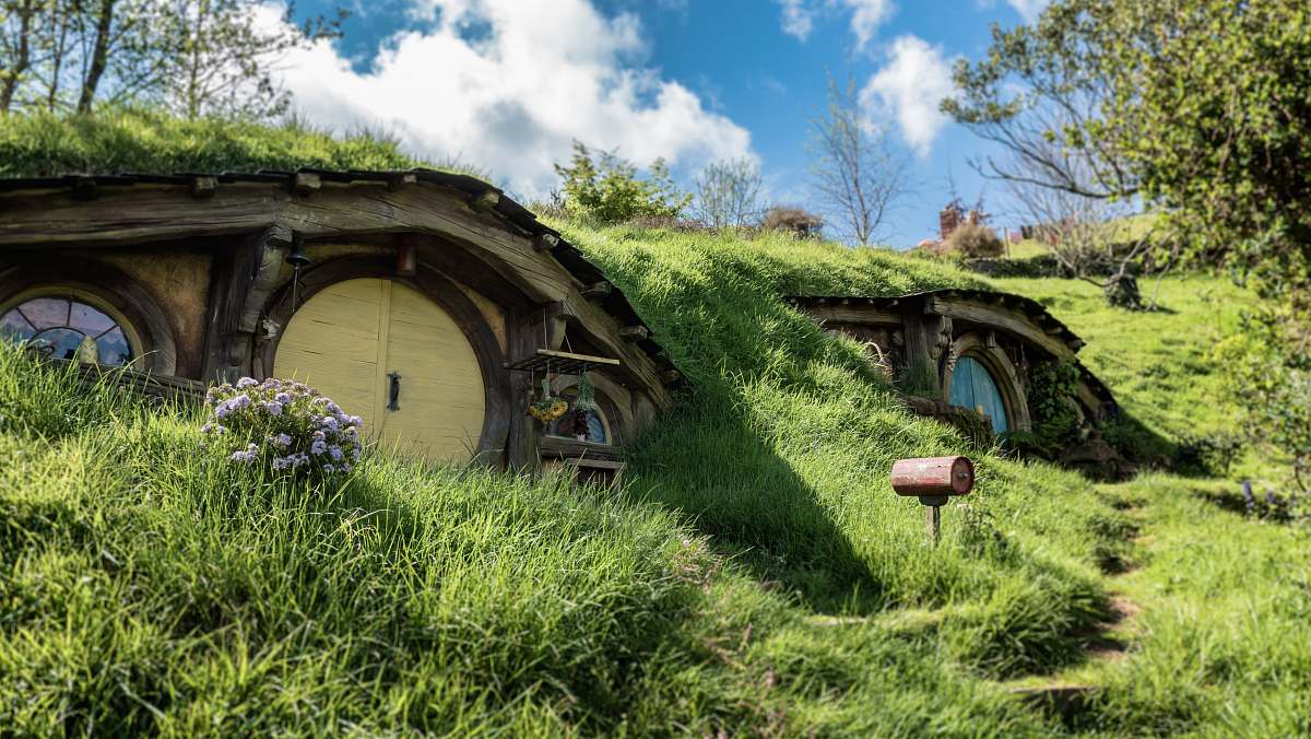 building landscape photography of brown wooden house with trees around hobbiton movie set